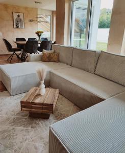 ein Wohnzimmer mit einem großen Sofa und einem Tisch in der Unterkunft Wunderschönes Haus am See - Seeblick, großer Garten, Südbalkon, Carport & Smart-TV in Gaienhofen