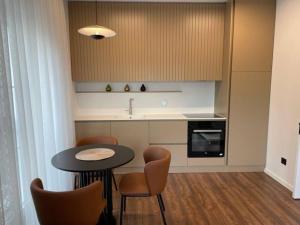 cocina con mesa, sillas y fregadero en Grandeur City Centre Apartment, en Pristina