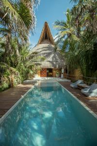 a resort with a swimming pool and a thatch roof at Casa Nalum in Tulum