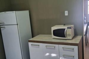 a microwave sitting on a counter next to a refrigerator at casa grande e confortável in Pirapora