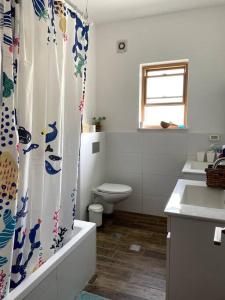 a bathroom with a toilet and a shower curtain at Quiet cottage in the pastoral Galilee hills in Hararit