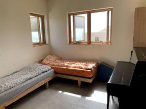 a bedroom with two beds and two windows at Quiet cottage in the pastoral Galilee hills in Hararit