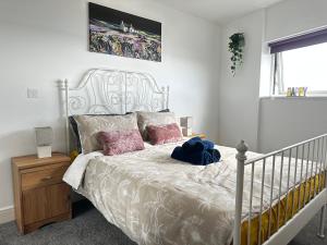 a bedroom with a white bed with pink pillows at Stunning Ocean & City View APT in Swansea