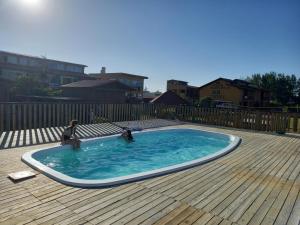 a small pool with two dolls in it on a wooden deck at Pousada Moradas do Sol Nascente in Passo de Torres