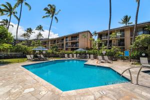 a swimming pool in front of a hotel with palm trees at Kona Makai 5307 in Kailua-Kona