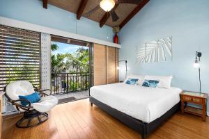 a bedroom with a bed and a chair and a balcony at Kona Makai 5307 in Kailua-Kona