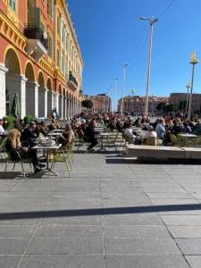 a large group of people sitting at tables outside a building at Spacious 3 bed apartment in the heart of Nice in Nice