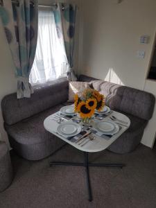 ein Wohnzimmer mit einem Tisch mit Tellern und einem Sofa in der Unterkunft Meadow bay Hayling Island-Iona in South Hayling