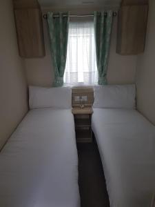 two beds in a small room with a window at Meadow bay Hayling Island-Iona in South Hayling