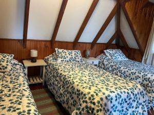 two beds in a room with wooden walls at Cabaña Ruca Quimey in Villarrica
