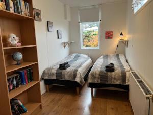 a bedroom with two beds and a book shelf at Cozy house by the river Ytri Rangá in Hella