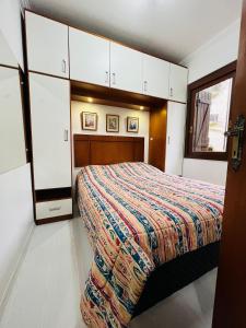1 dormitorio con 1 cama y armarios blancos en MRG Bavária 1D Próximo ao centro Gramado, en Gramado