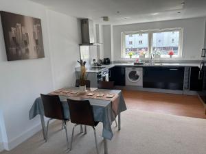 a kitchen with a table and chairs in a kitchen at Water Front APT Walk to the Beach & City Centre in Swansea