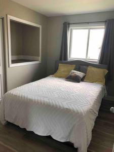 1 dormitorio con 1 cama blanca y ventana en Hinton Alberta Vacation Home, en Hinton