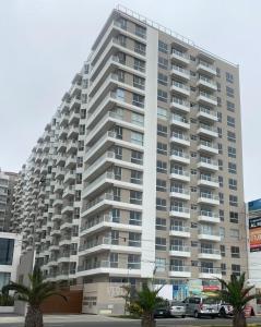um grande edifício de apartamentos com palmeiras em frente em Tú hogar frente al mar em Lima