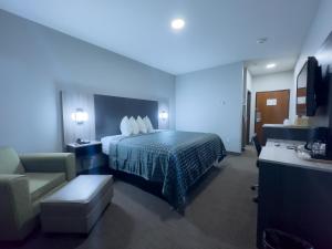 una camera d'albergo con letto e sedia di American Inn Madill a Madill