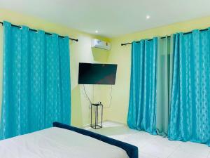 een slaapkamer met blauwe gordijnen, een bed en een tv bij Villa avec piscine in Somone