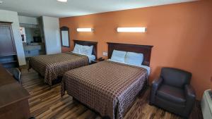 a hotel room with two beds and a chair at Hillcrest Inn & Suites Ozona in Ozona