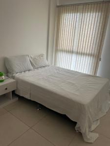 Apartamento Rio Marina Resort في مانغاراتيبا: سرير أبيض في غرفة بها نافذة