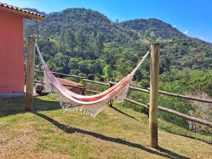 a hammock on a fence with a mountain in the background at Pousada Vale das Araucárias in Santo Antônio do Pinhal