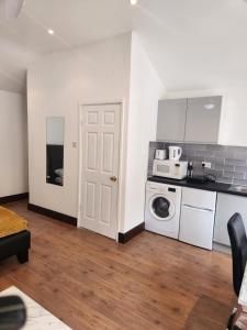 een keuken met een wasmachine en een witte deur bij Cosy Studio Flat in Bexleyheath