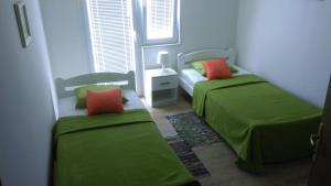 2 camas en una habitación con sábanas verdes y almohadas de color naranja en Holiday Home Rudelic, en Lukovo Šugarje