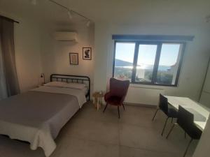 伊古邁尼察的住宿－Μοντέρνο Στούντιο, με Θέα，卧室配有床、椅子和窗户。