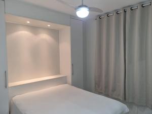 um quarto branco com uma cama e uma cortina em Estúdio Beira Mar em Florianópolis