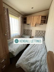 two beds in a small room with a kendall left at Amble Retreat, Seal Bay Resort in Selsey