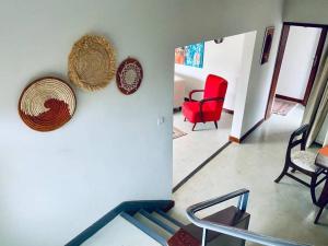 Kololo 3BR with Garden, 500m to Acacia Mall في كامبالا: غرفة معيشة بها كرسي أحمر وسلة معلقة على الحائط +15 صورة