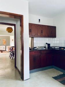 a kitchen with wooden cabinets and a dining room at Spacious Residence with Garden Close to Acacia Mall Kololo in Kampala