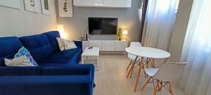 a living room with a blue couch and a white table at Drzewna Apartamenty - Niepodległości in Zielona Góra