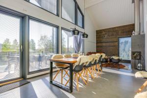 - une salle à manger avec une table, des chaises et des fenêtres dans l'établissement Luksushuvila Villa Marvik, à Jämsä