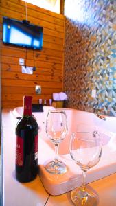 a bottle of wine and two wine glasses on a counter at Cabanas Rural Colina Do Sol in Cambará