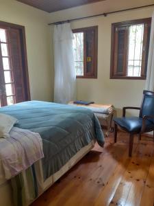 - une chambre avec un lit, une chaise et des fenêtres dans l'établissement Chalé ensolarado, bairro Frei Rogerio, à Lages