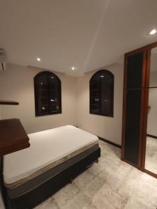 a bedroom with a large bed with two windows at Casa em mangaratiba in Mangaratiba