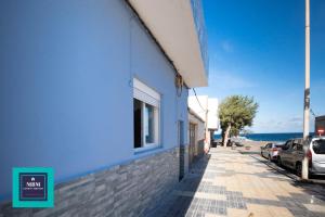 un bâtiment bleu sur un trottoir à côté de l'océan dans l'établissement Mara 1 Playa del Burrero junto al mar wifi gratis, à Ingenio