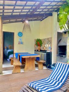 a room with a table and benches and a kitchen at Casa Hibiscus Beach Club Ipioca Maceió in Maceió