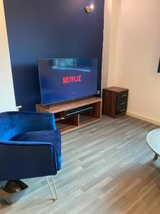 een woonkamer met een blauwe stoel en een tv bij Spacious 2 Bedroom City Centre Apartment by Cloud Suites in Manchester