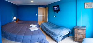1 dormitorio azul con 2 camas y mesita de noche en Casona confortable y cálida con hermoso jardín en Río Gallegos
