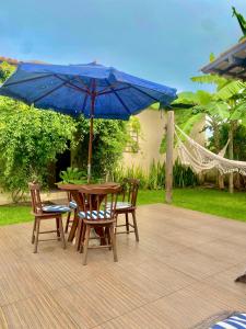 uma mesa e cadeiras de madeira com um guarda-sol azul em Casa Hibiscus Beach Club Ipioca Maceió em Maceió