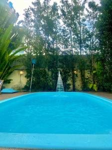 uma grande piscina azul num quintal em Casa Hibiscus Beach Club Ipioca Maceió em Maceió