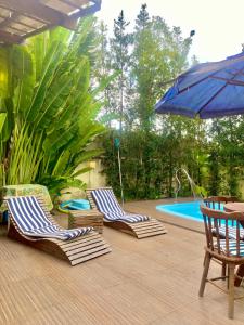 zwei Stühle und ein Sonnenschirm neben einem Pool in der Unterkunft Casa Hibiscus Beach Club Ipioca Maceió in Maceió