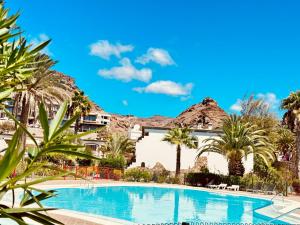 a swimming pool in front of a resort with palm trees at Playa del Cura in Playa del Cura