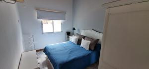 1 dormitorio con 1 cama con sábanas y almohadas azules en Verto Departamentos en Pinamar