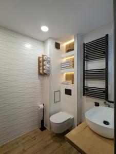a bathroom with a white toilet and a sink at Pine & Wine Sauna Apartment in Pamporovo