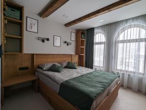 a bedroom with a bed and two windows at Pine & Wine Sauna Apartment in Pamporovo