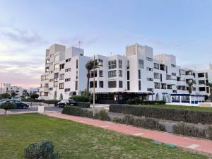 un gran edificio de apartamentos blanco con aparcamiento en Primera linea de Playa de Martina en Almerimar