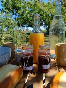 uma mesa com pão e frascos de compota e sumo de laranja em Roulotte Ô Rêves Atypiques em Boucé