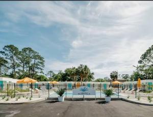une clôture avec des parasols en face d'une piscine dans l'établissement Gulf Shores Getaway steps away from the pool!, à Gulf Shores